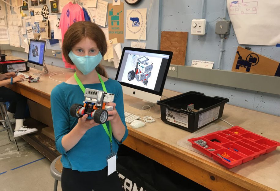 female student holding up her lego robot