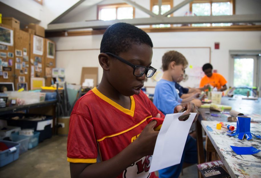 A young boy cutting a piece of paper.