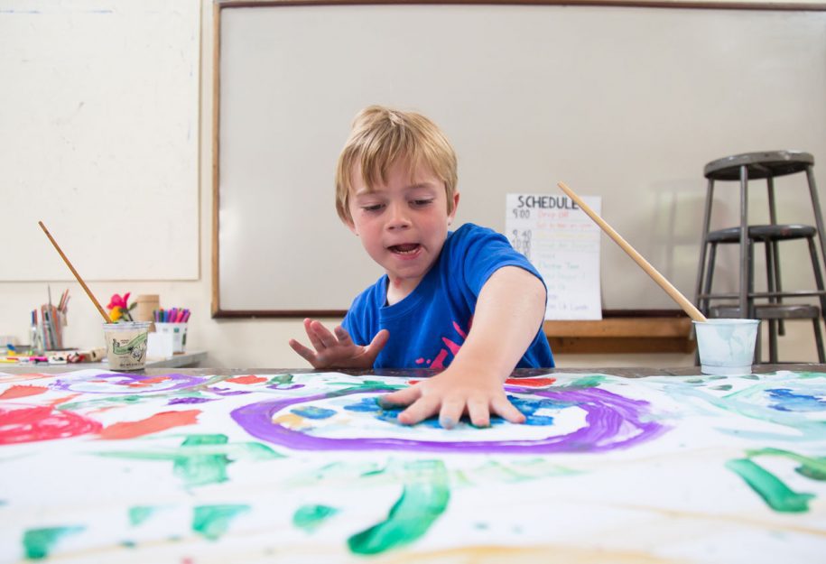 A young boy fingerpainting