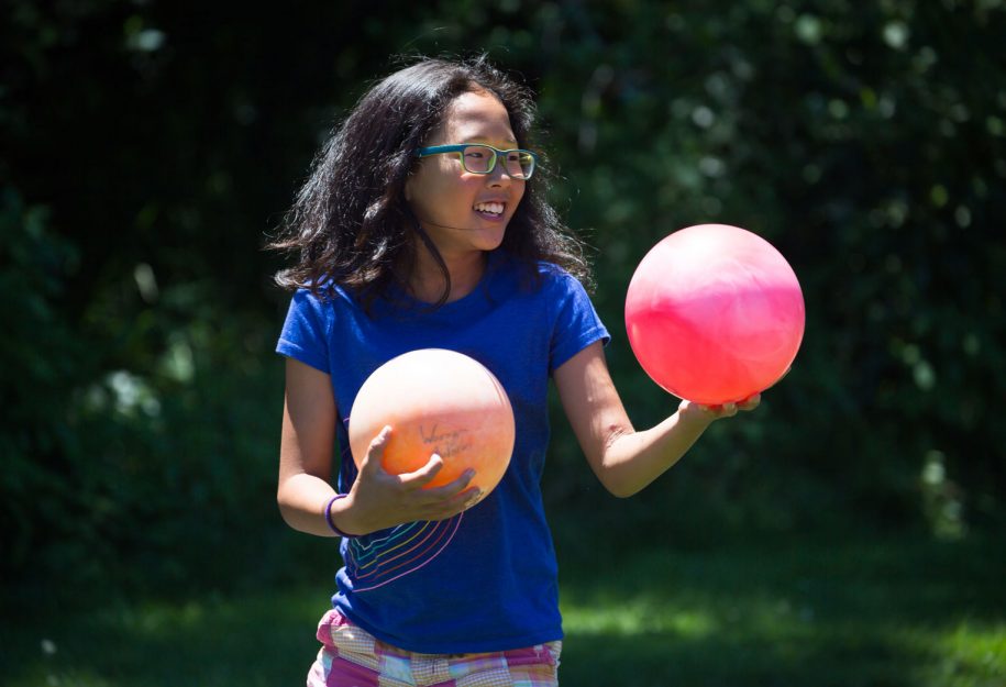 A young girl holding two balls
