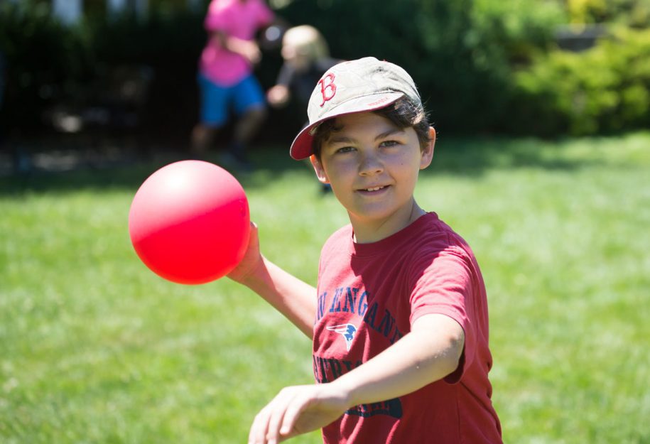 a young boy about to throw a red ball